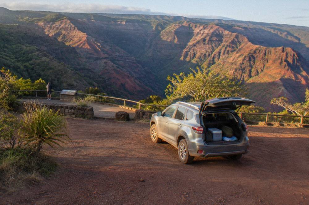 A parking area beside a canyon overlook with layered red rock walls in the distance