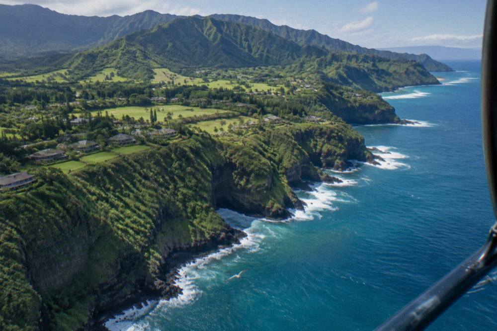 Aerial view of jagged green sea cliffs along a tropical coastline