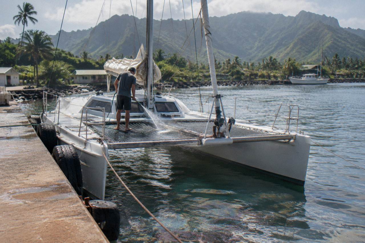 A catamaran cruising along green sea cliffs on the Na Pali Coast of Kauai