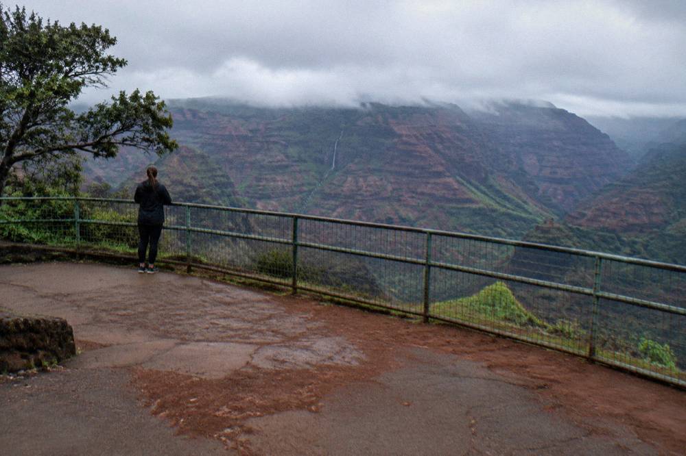 A look-out point above a wide red and green canyon with mist resting on distant ridges