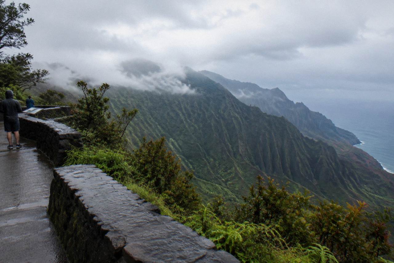 A dense green tropical valley on Kauai with layered mountain ridges under soft clouds