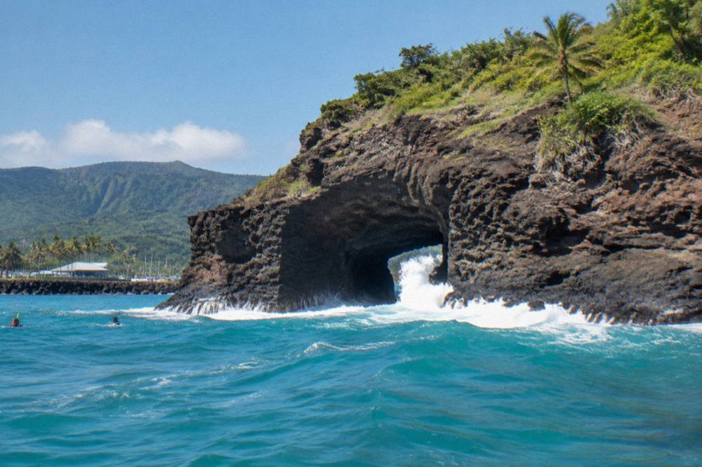 Turquoise water breaking against a sea arch in a rocky coastline