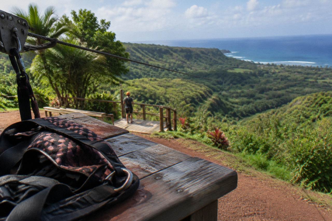 A long zipline cable stretching over a green Kauai valley
