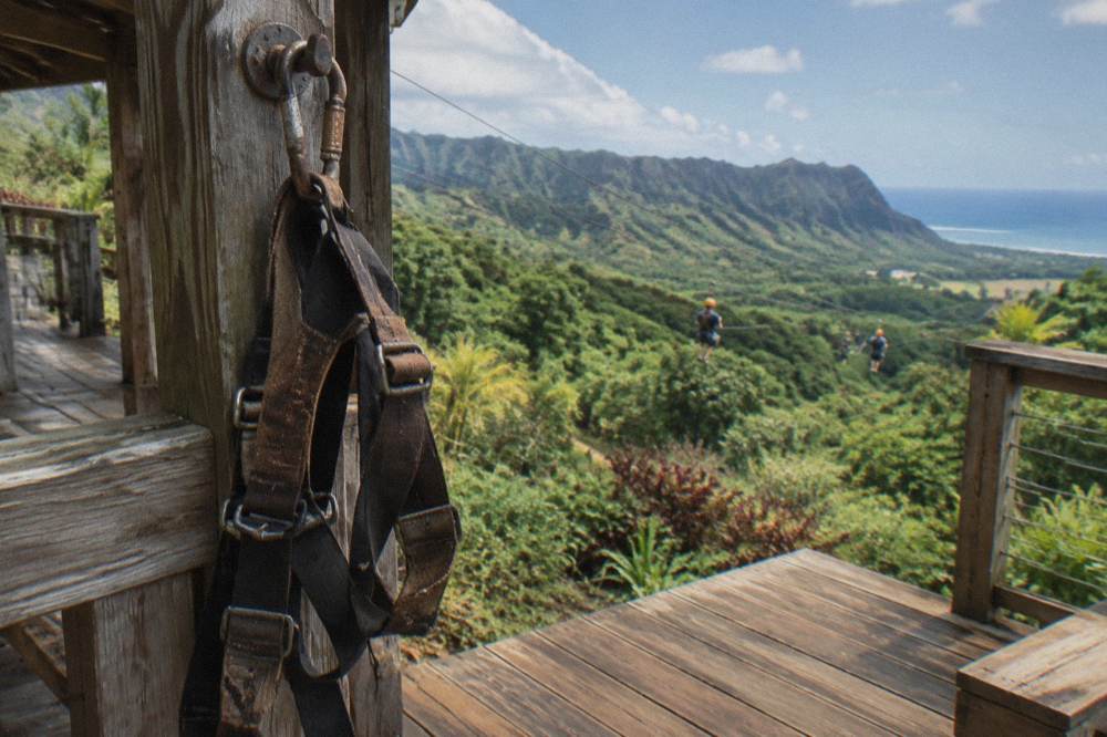 A zipline platform above a green Kauai valley with forest ridges beyond