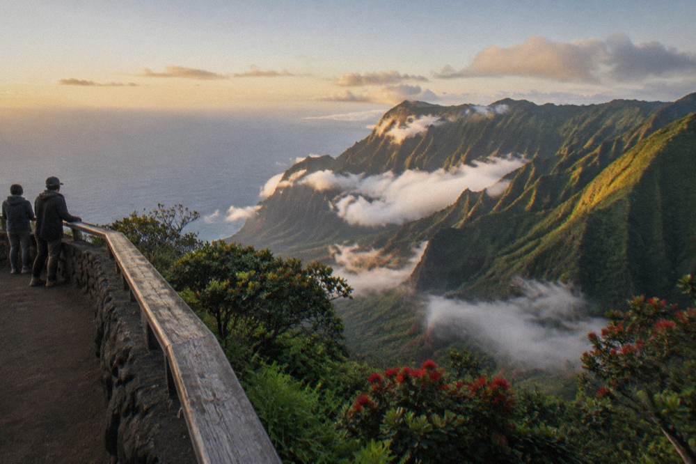 Morning sunlight over a green mountain ridge with low clouds drifting through the valley