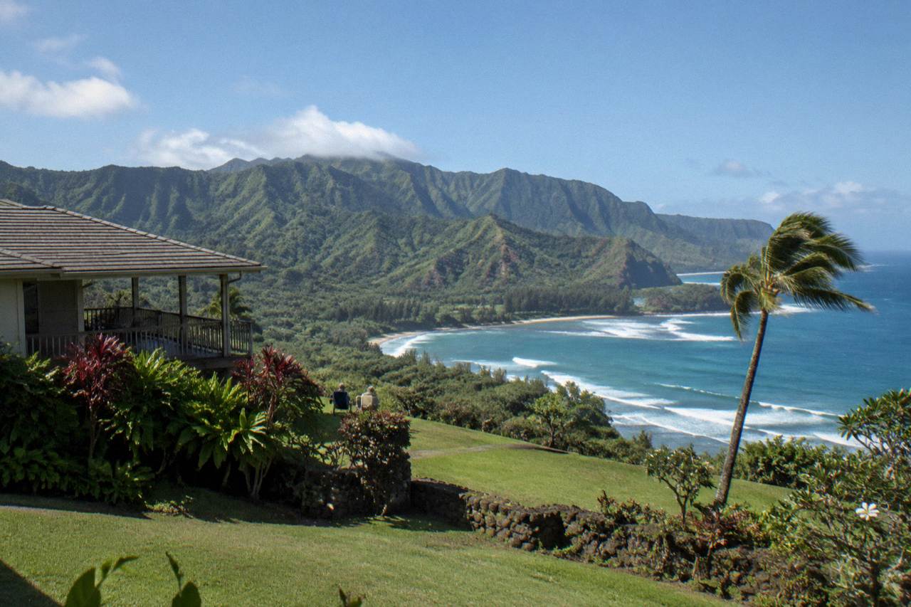 Turquoise ocean water breaking against tall green sea cliffs on a calm morning