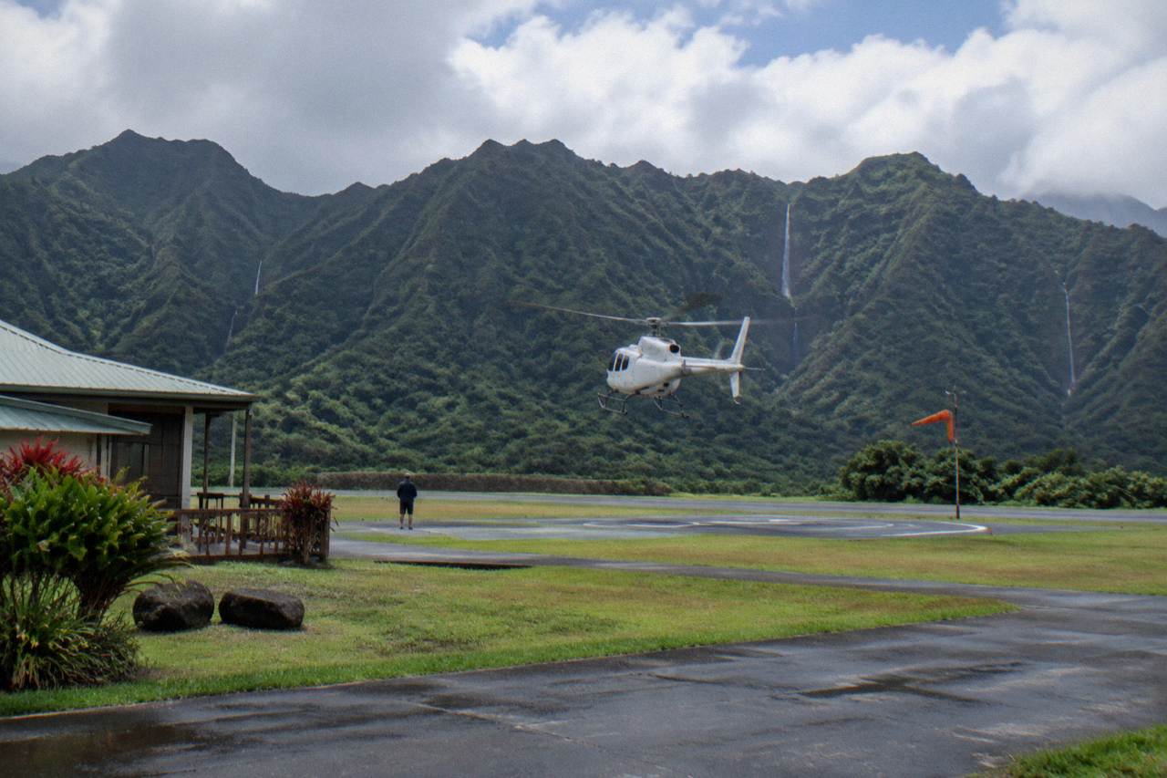 A helicopter flying over deep green Kauai valleys and ribbons of waterfalls