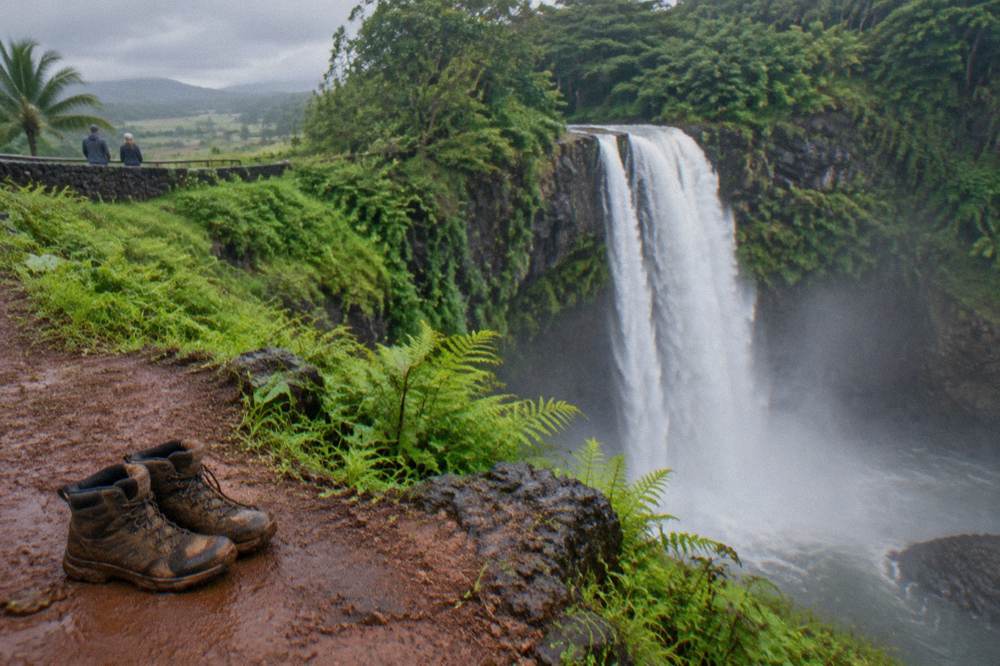 A waterfall flowing full over a green cliff face after rain