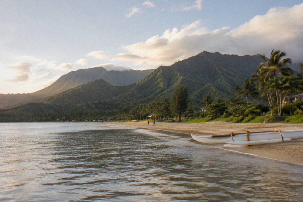 Long crescent of golden sand curving between green mountain ridges and a calm bay.