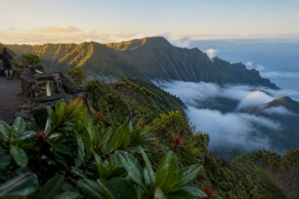 Morning sunlight over a green mountain ridge with low clouds in the valleys