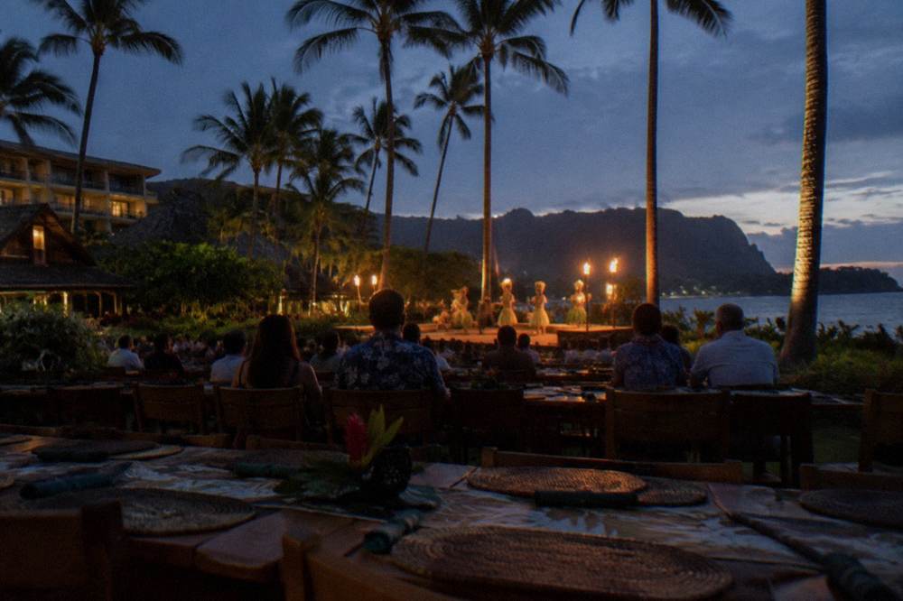 Guests seated at long tables facing a torch-lit stage before a performance