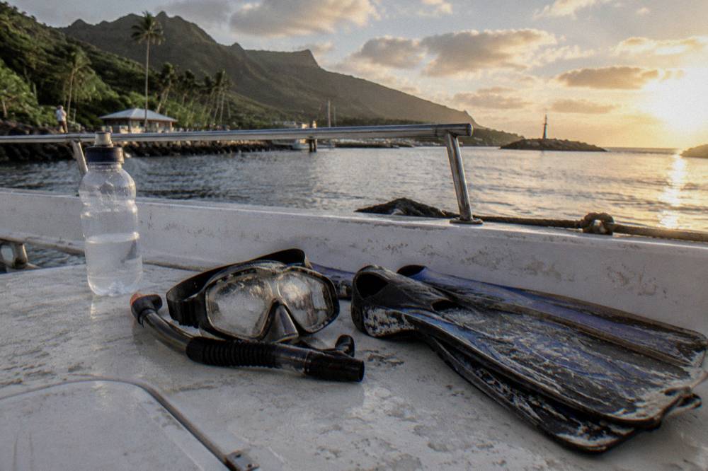 Snorkel mask and fins resting on a boat deck with ocean horizon beyond