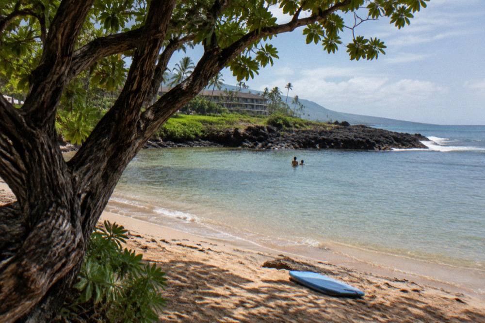 A calm protected sandy beach cove with rocky point and clear shallow water