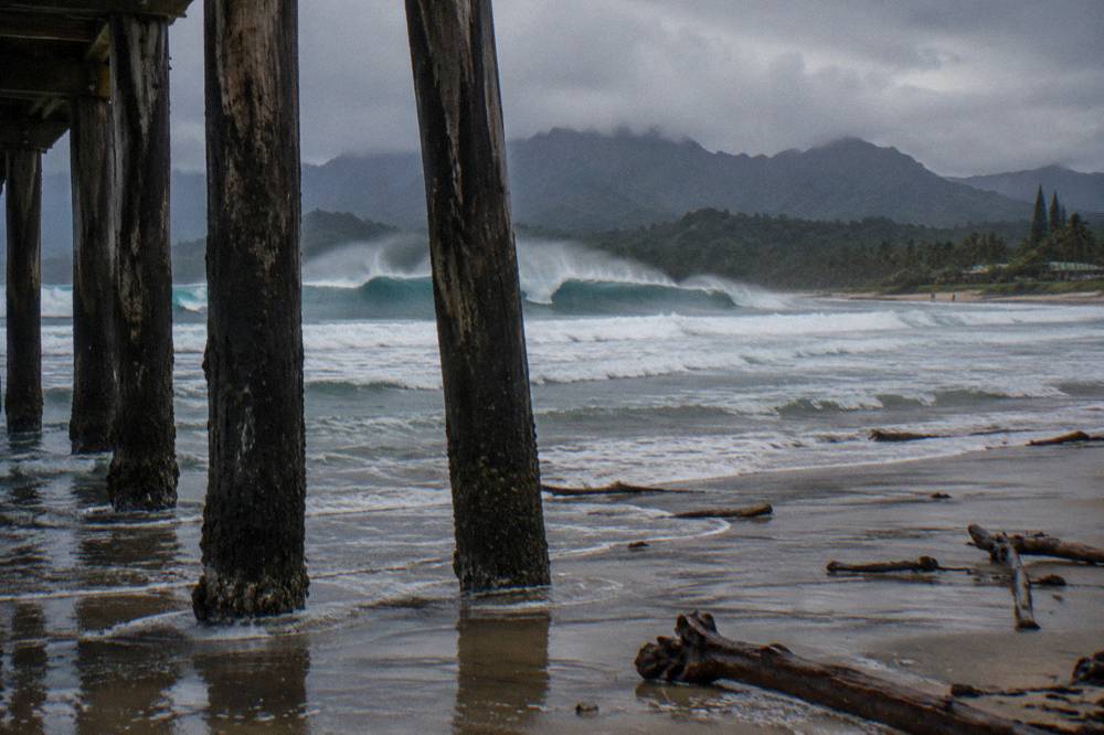 Waves breaking along a rocky north shore beach under a grey sky