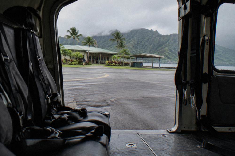 Helicopter interior showing passenger harness straps and an open doorway