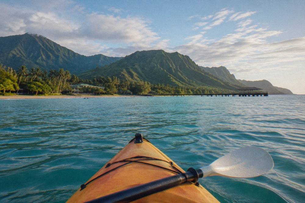 A single kayak on turquoise open water with a distant green peninsula