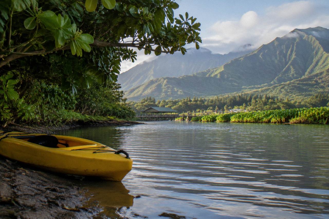 A kayak resting on a calm river surface with green jungle hills rising behind it