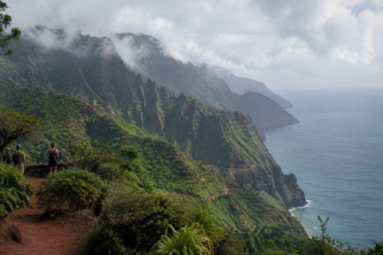 Green sea cliffs of the Na Pali Coast rising above calm Pacific water