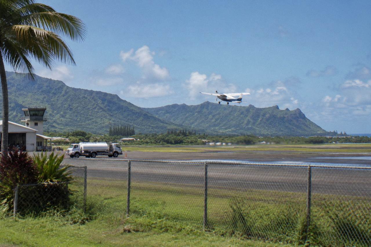A small sightseeing airplane flying above green Kauai ridgelines and the ocean