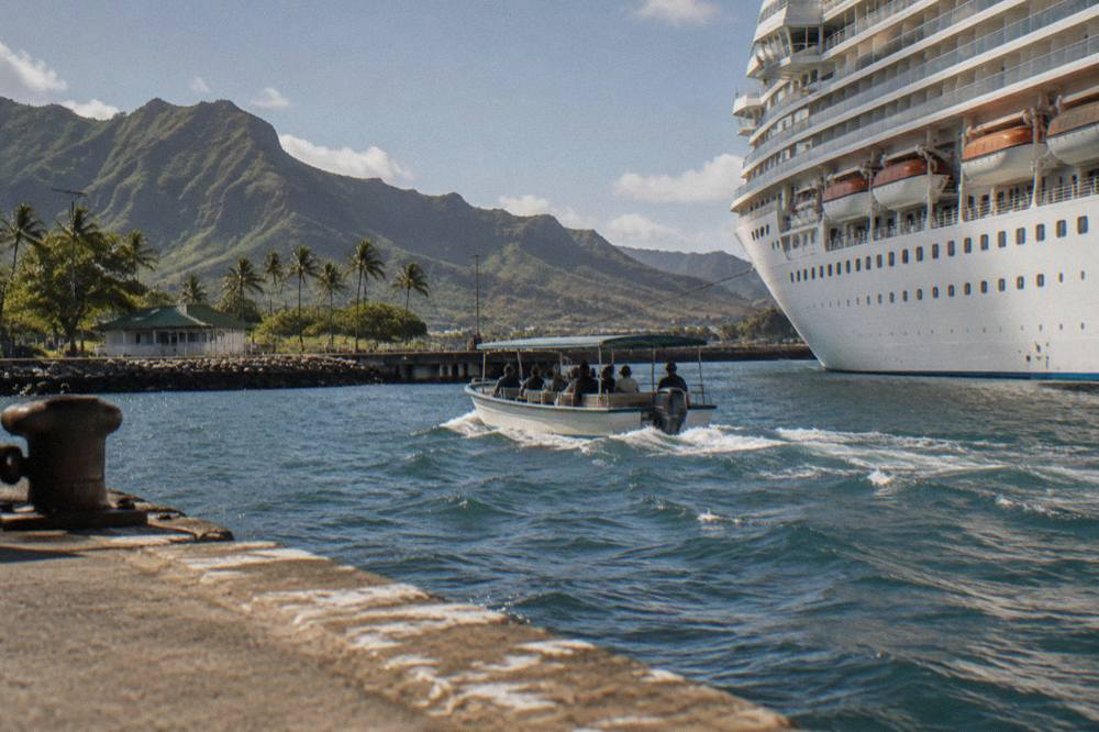 Cruise ship docked at a harbor with a small boat tour boat passing in the foreground