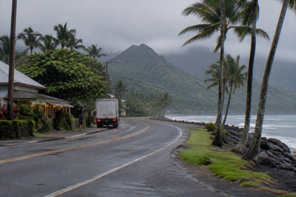 Quiet two-lane coastal road curving along a green shoreline