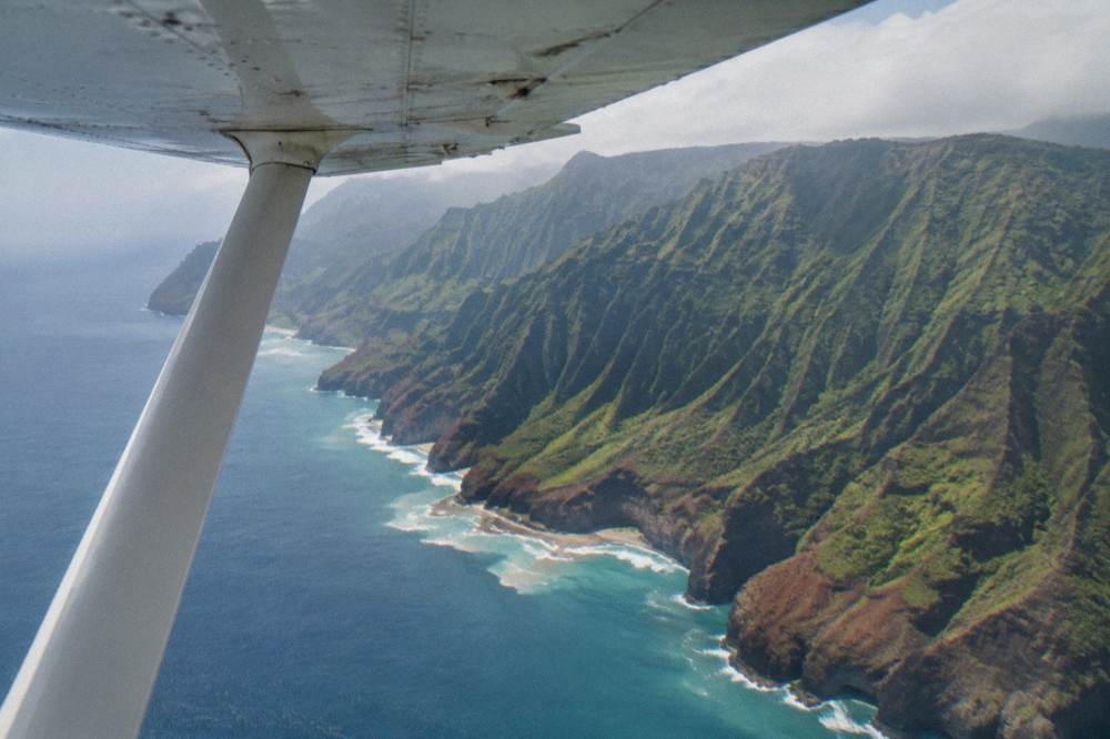 A small fixed-wing tour airplane flying above a coastline with cliffs