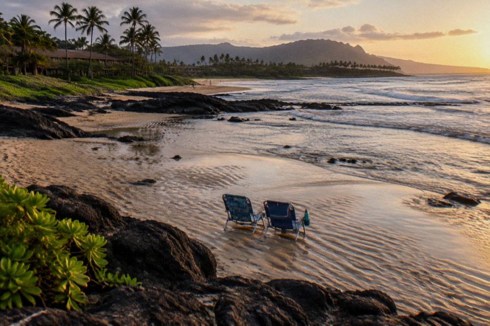 Two beach chairs side by side on a quiet stretch of golden sand at low tide