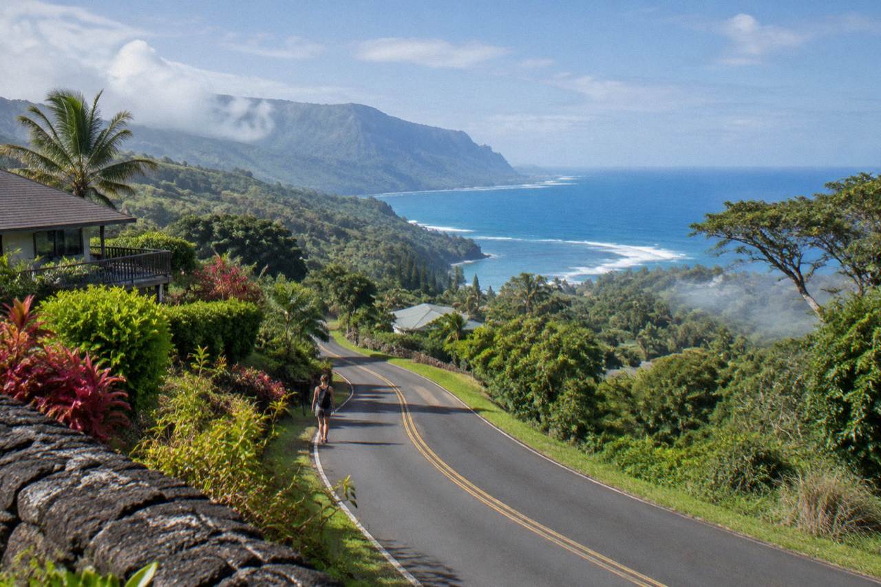 A winding road through green Kauai hills with ocean in the distance