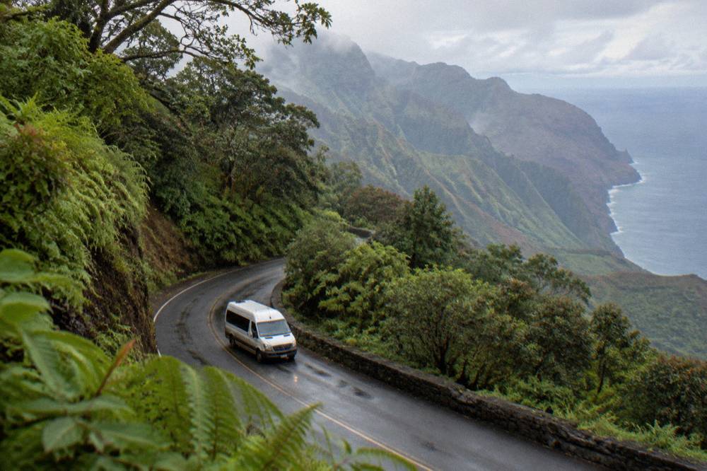 Small tour van on a winding road through tropical forest