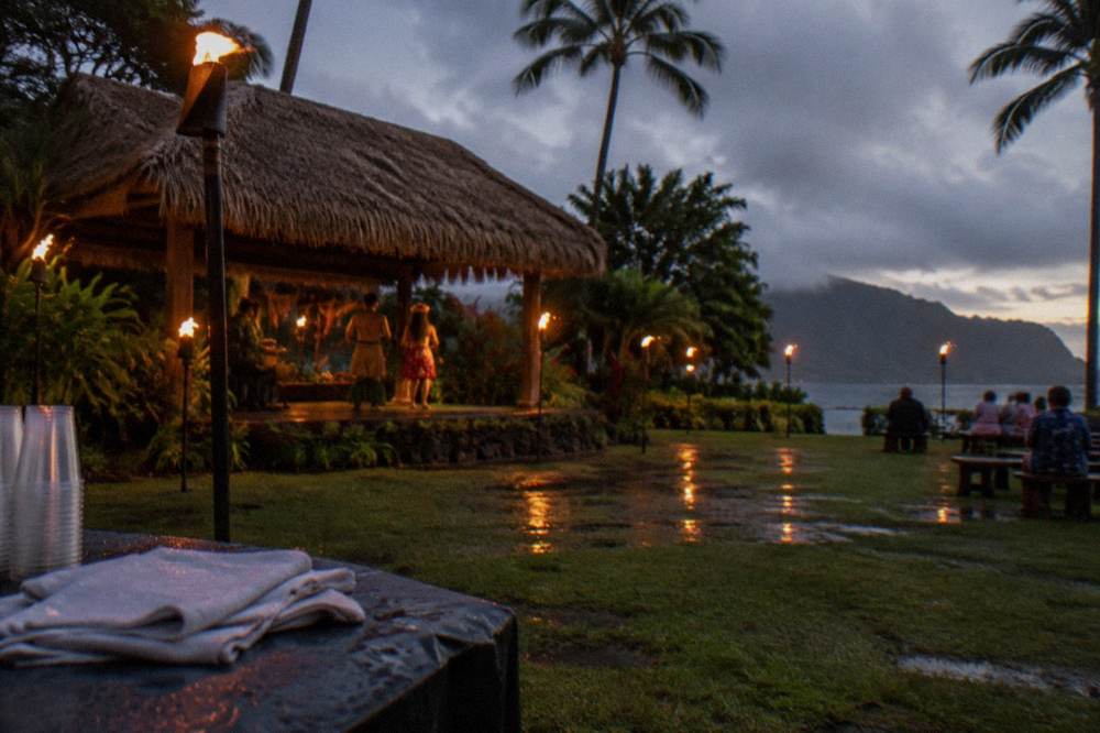 Torches glowing at an outdoor Hawaiian luau stage before a show.