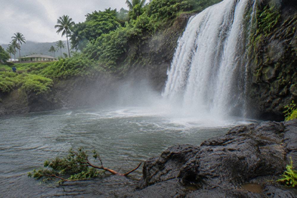 A wide waterfall plunging into a mist filled pool at the base of a basalt cliff