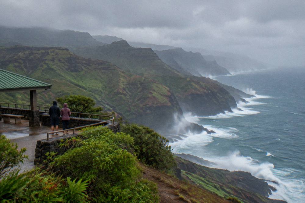 Large ocean swells breaking against dark rock formations along a steep coastline