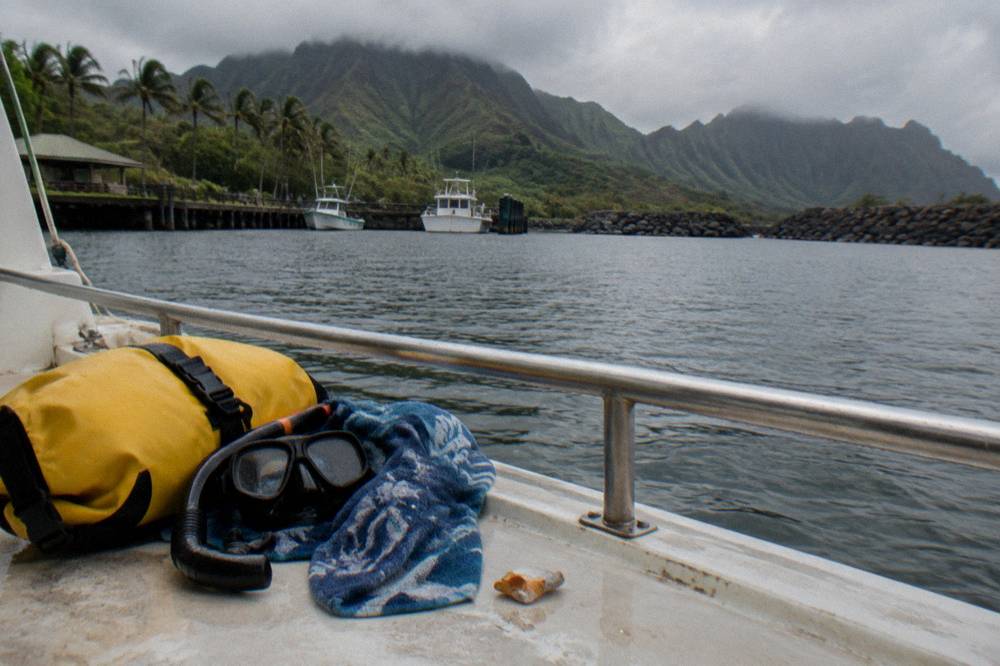 A dry bag, snorkel mask and towel arranged on a boat deck bench beside a rail and open water