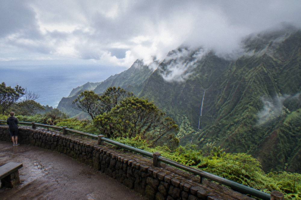Waterfall dropping down a dark green mountain wall into a narrow valley