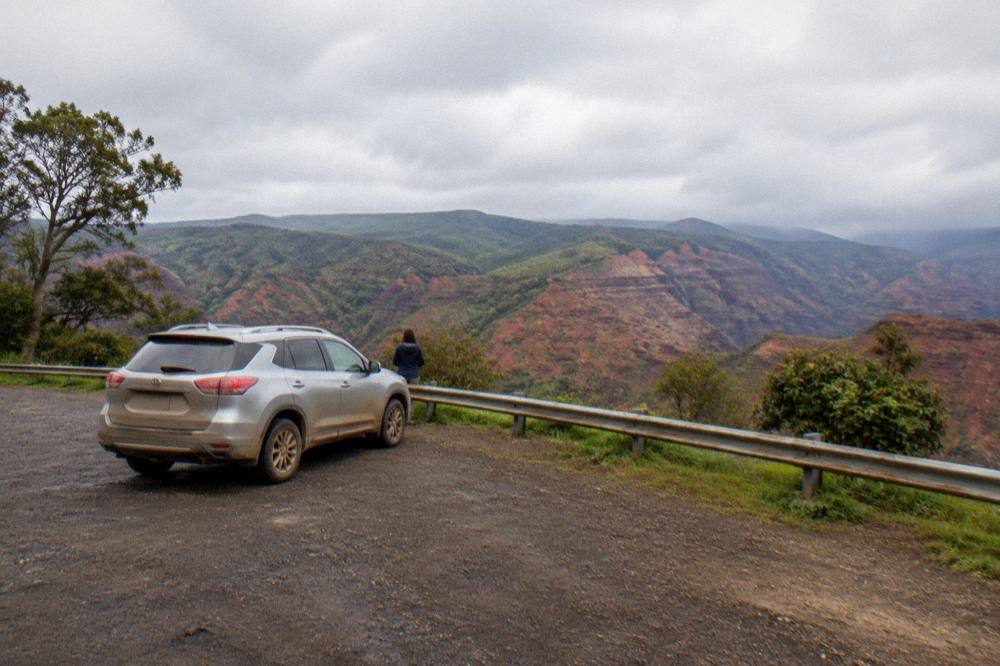 Car parked at an empty roadside pullout above a wide red gorge
